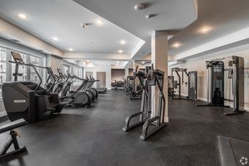 A spacious gym with a variety of equipment including treadmills, elliptical machines, and weight machines.